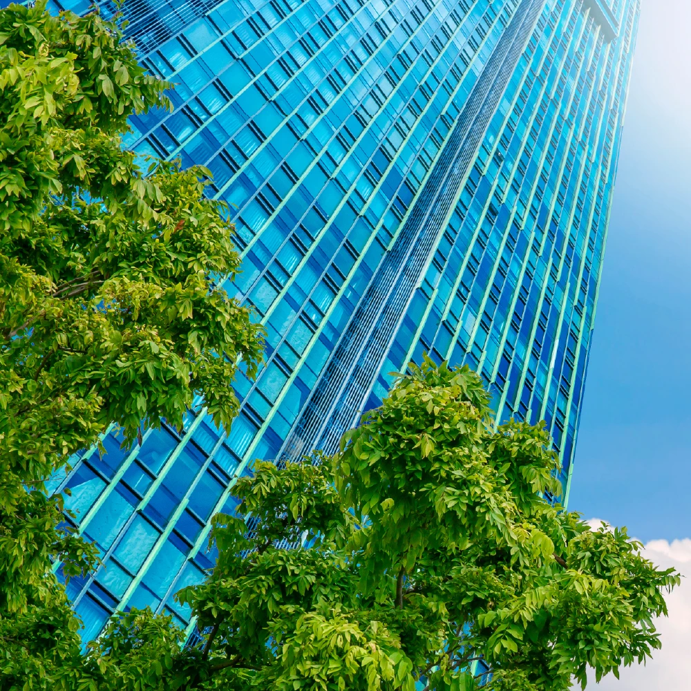 A tall high rise building surrounded by greenery.