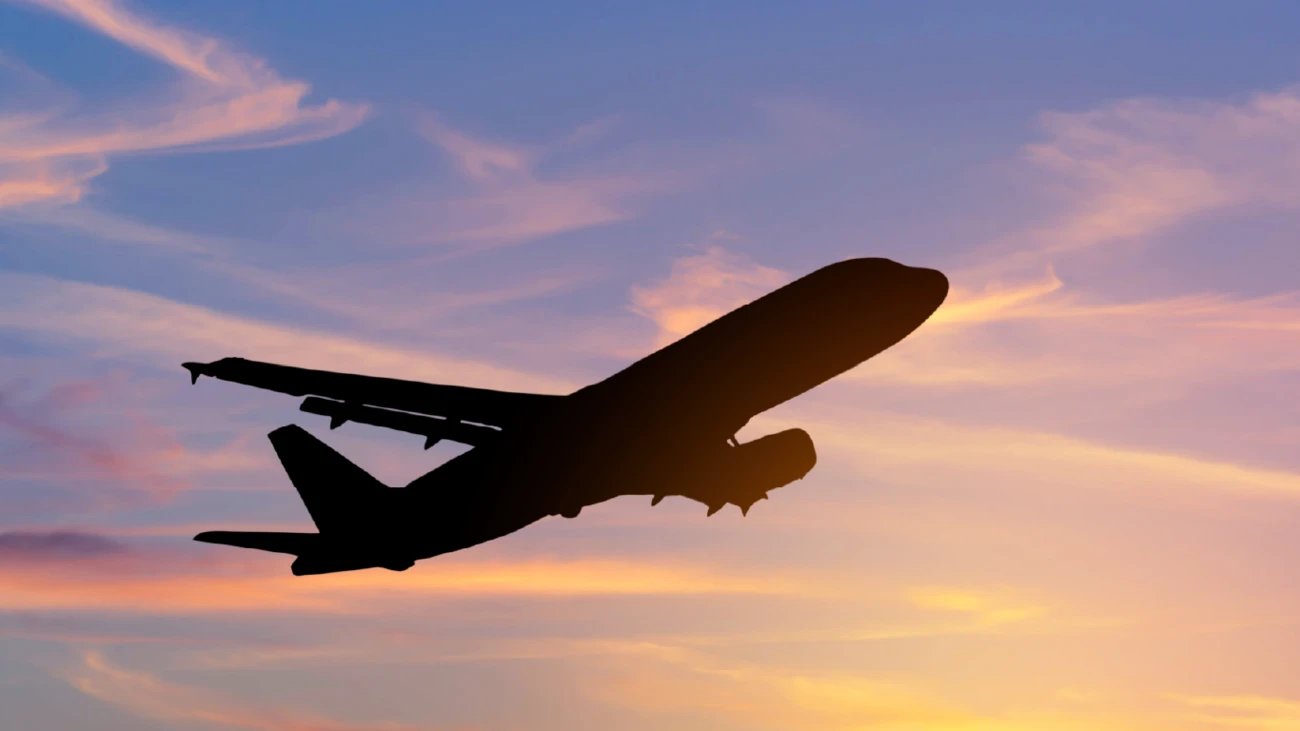Flying aeroplane silhouetted against a sunset.